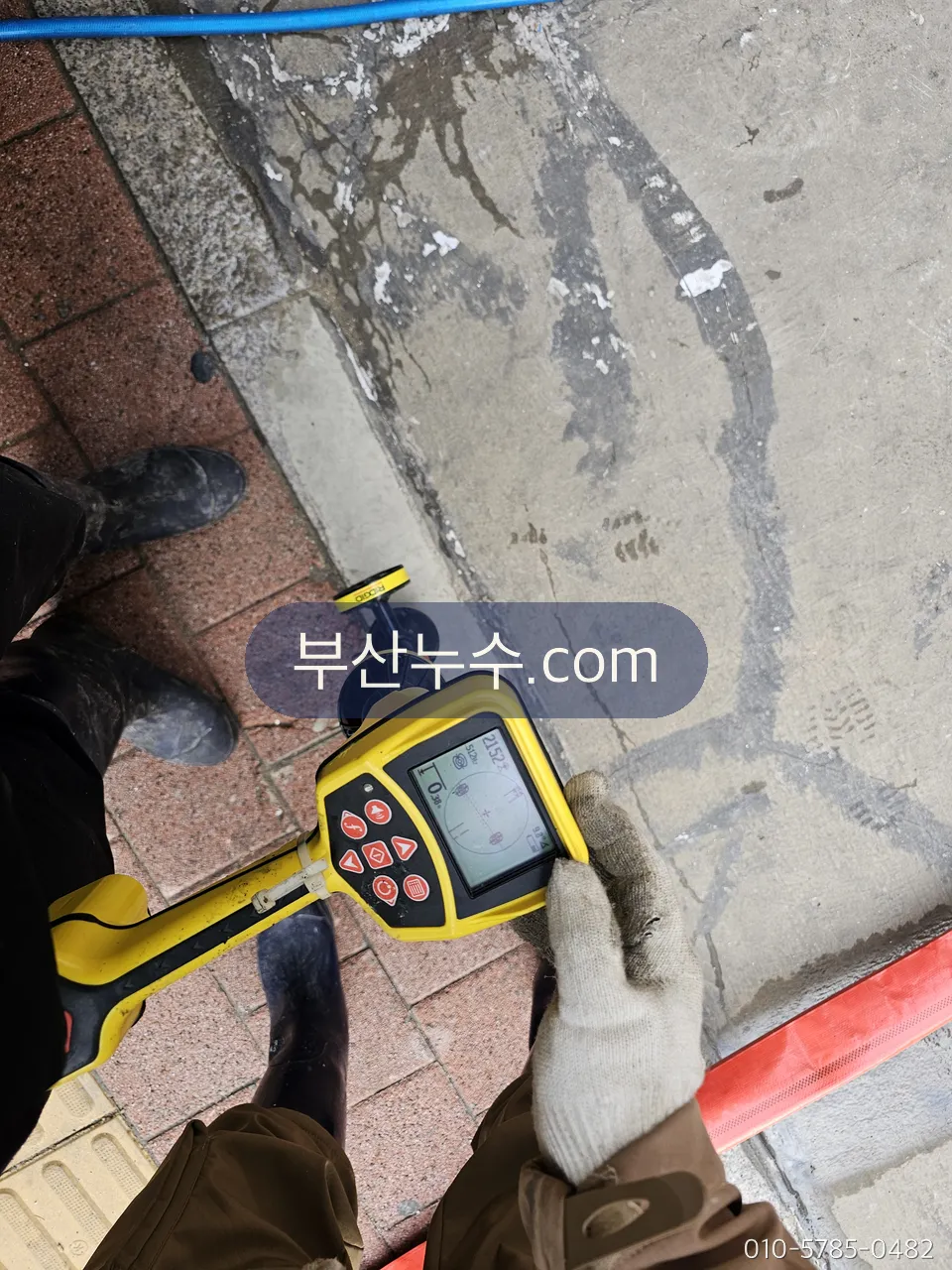 바닥에 탐지기를 대고 배관 경로를 따라가는 작업